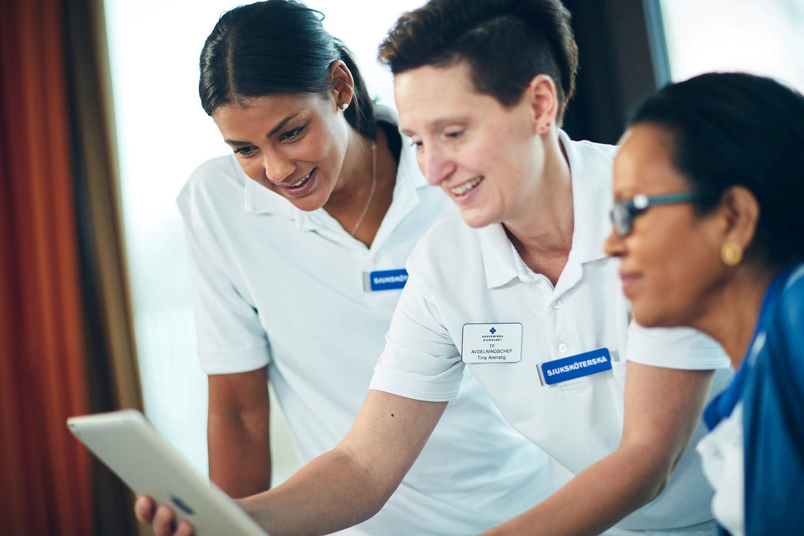 Illustration som visar tre vårdpersoner. Personerna tittar på en surfplatta och ser glada ut.